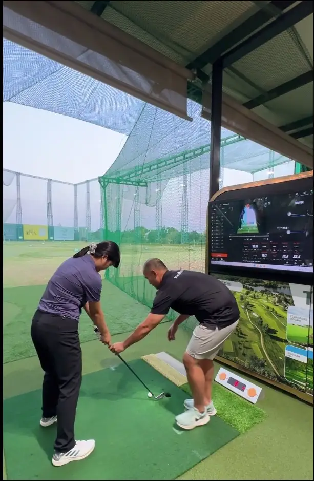 A golfer training with a coach in front of a Rapsodo screen